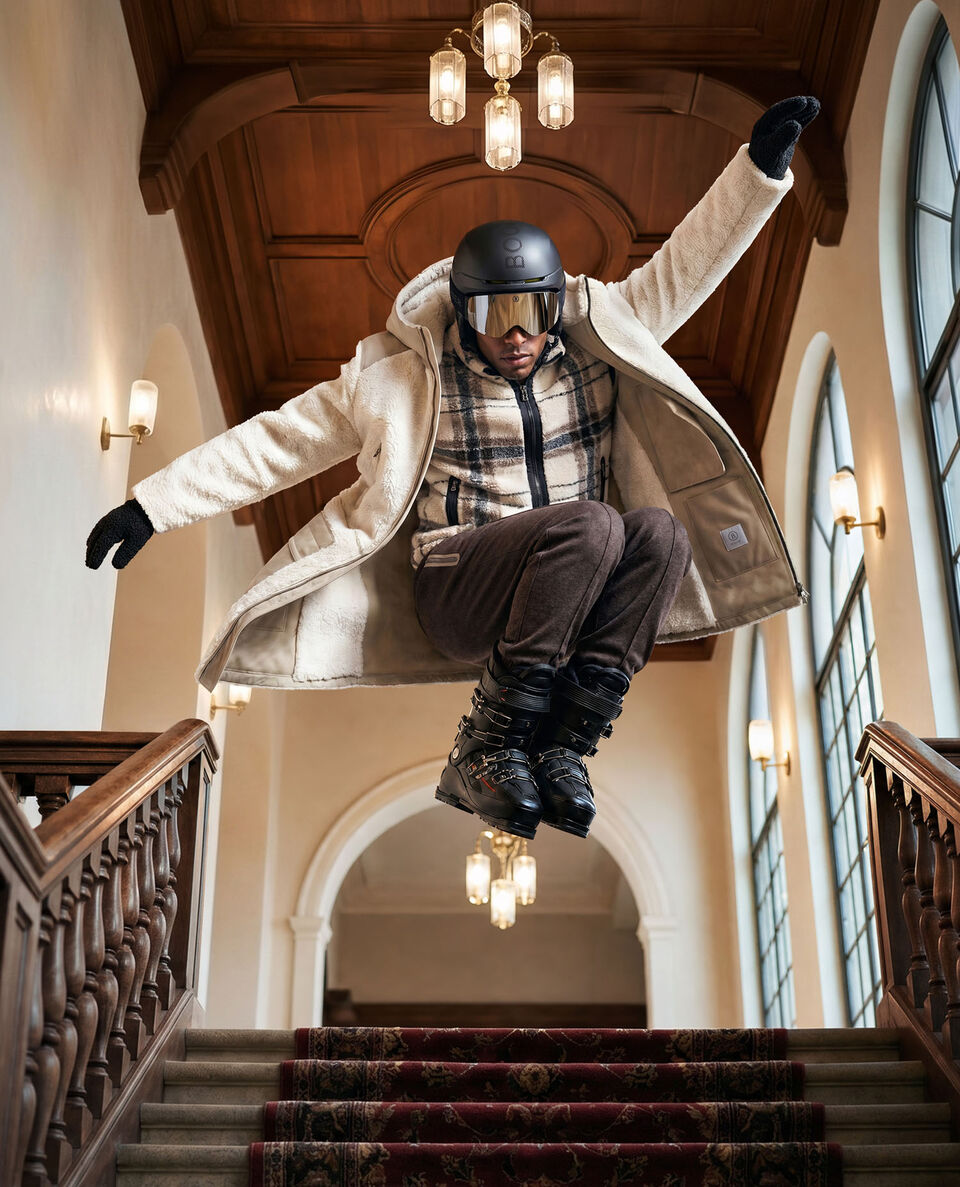 The model in a dynamic pose wears the Soan coat layered over the checked Kristian mid-layer.