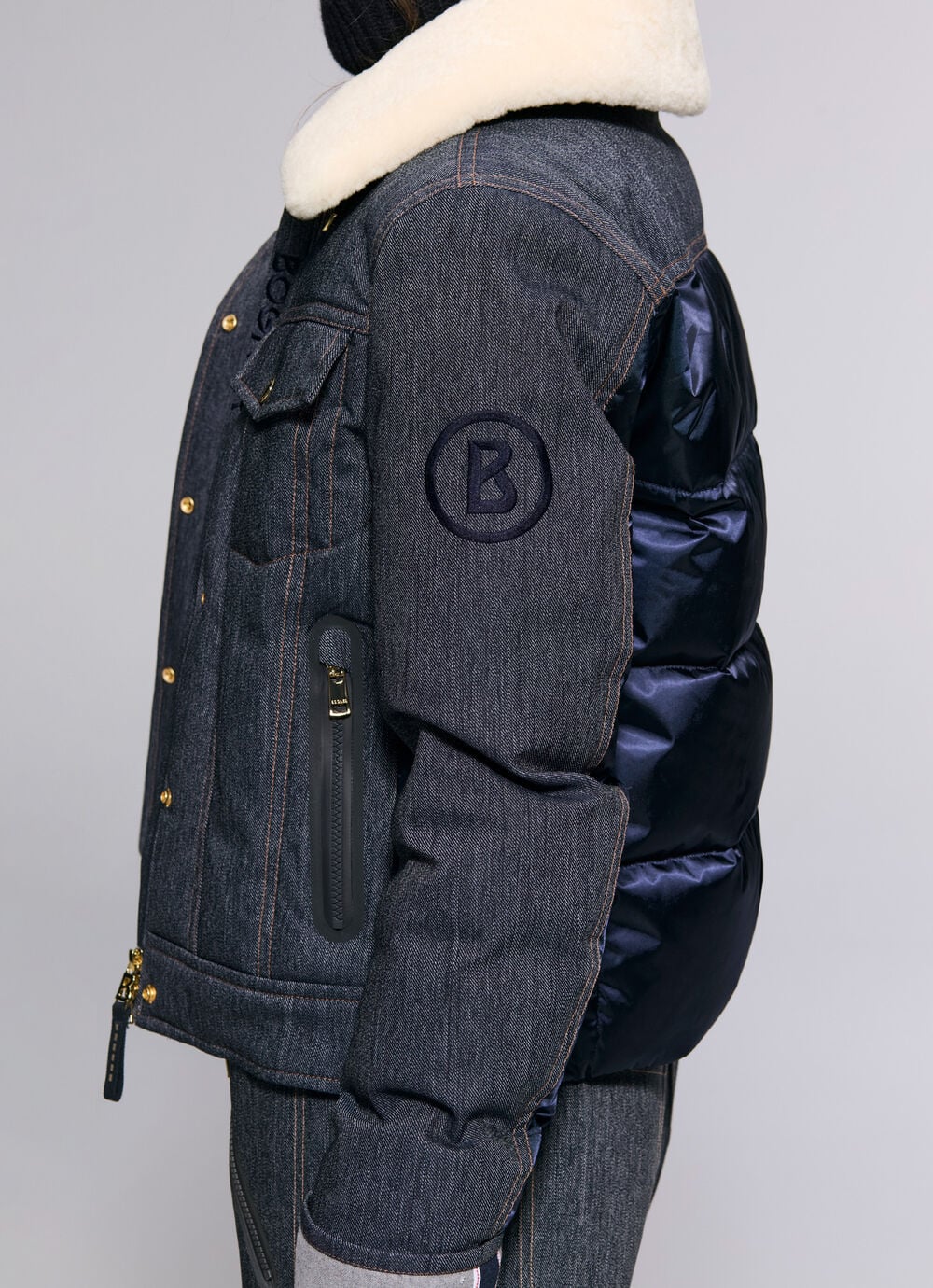 Das Damen Model pr&auml;sentiert Skijacke Denna aus Denim mit kontrastierendem Fellkragen und Satin-Einsatz auf der R&uuml;ckseite. Eine &bdquo;B&ldquo;-Logo-Stickerei am &Auml;rmel rundet das Design ab.