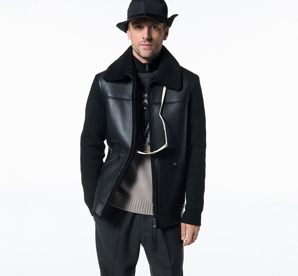 The male model wears a black baseball cap and sunglasses, hanging around his neck.