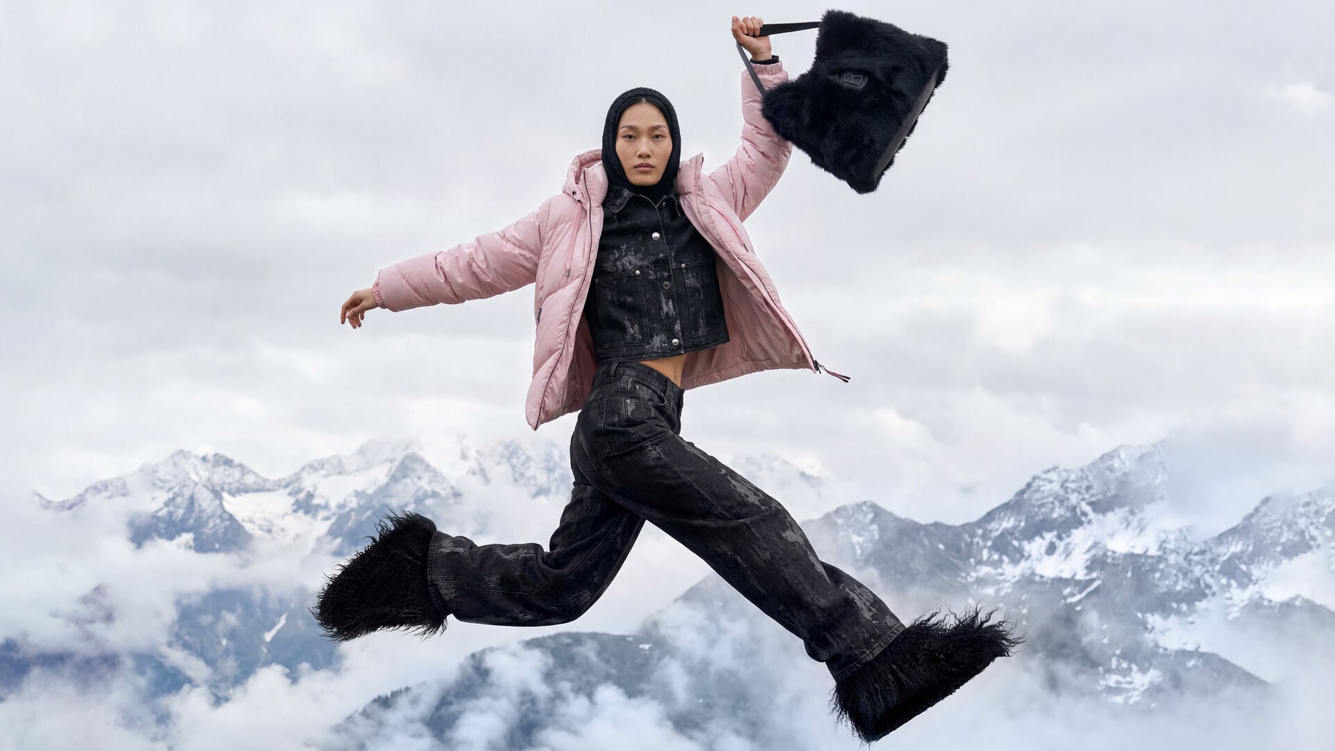 The female model is shown in a dynamic pose, wearing a coordinated outfit consisting of a jacket and jeans, paired with a handbag and a pink down jacket.