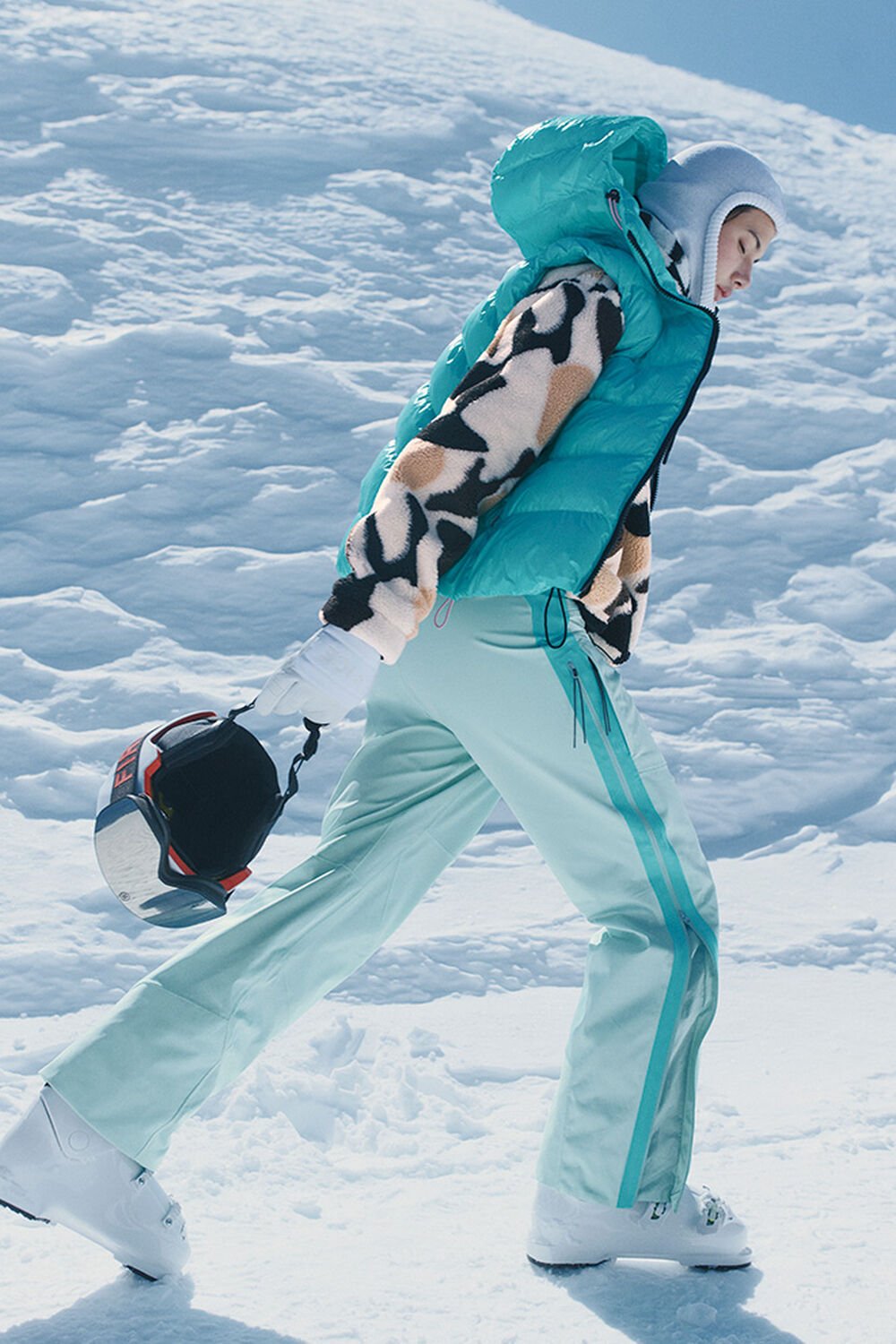Ein dynamischer Damen Ski Look, bestehend aus Shiny Puffer und Hose in Mint, darunter eine Multicolor-Fleecejacke.