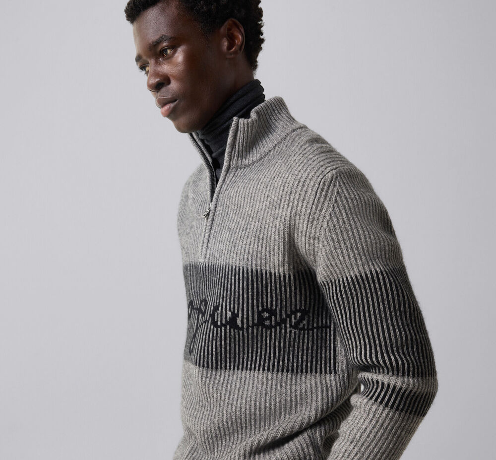 Men's model wearing the grey and black Loris yak half-zip sweater featuring a label logo on the front.