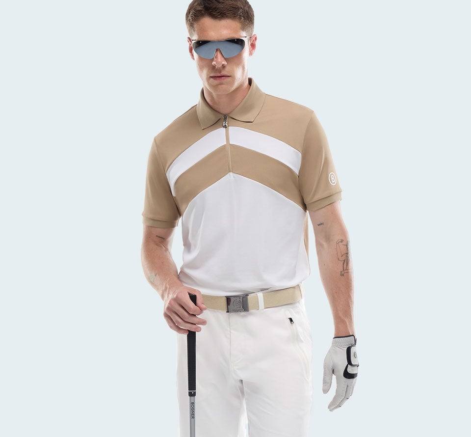 The male model is wearing a polo shirt with a short zip and a white and beige-coloured &lsquo;W&rsquo; motif, paired with white trousers and a belt.