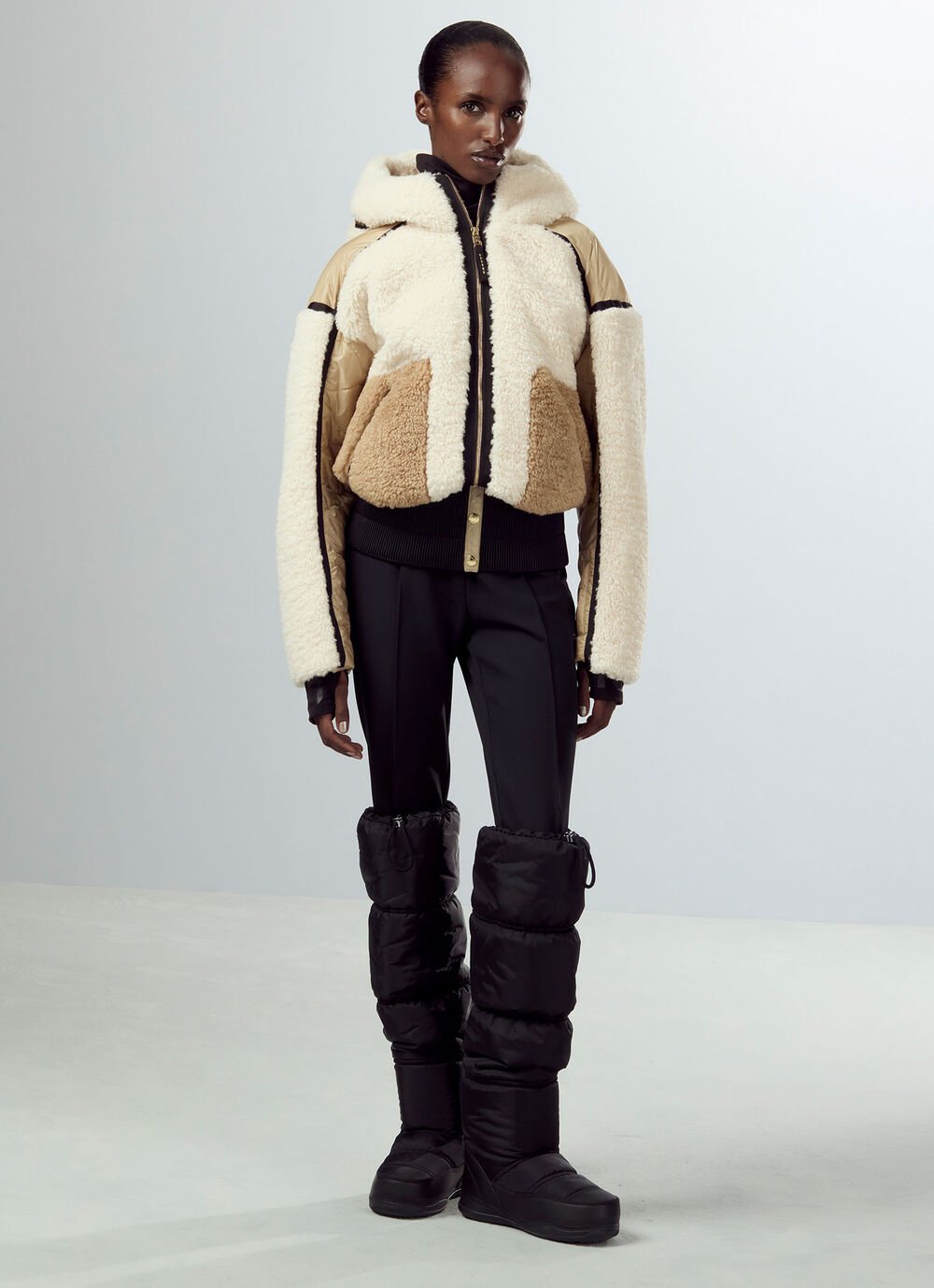 Skijacke Kora mit Patchwork-Partien aus Teddyfell wird hier als Hingucker zu schwarzer Steghose und kniehohen Boots gezeigt.
