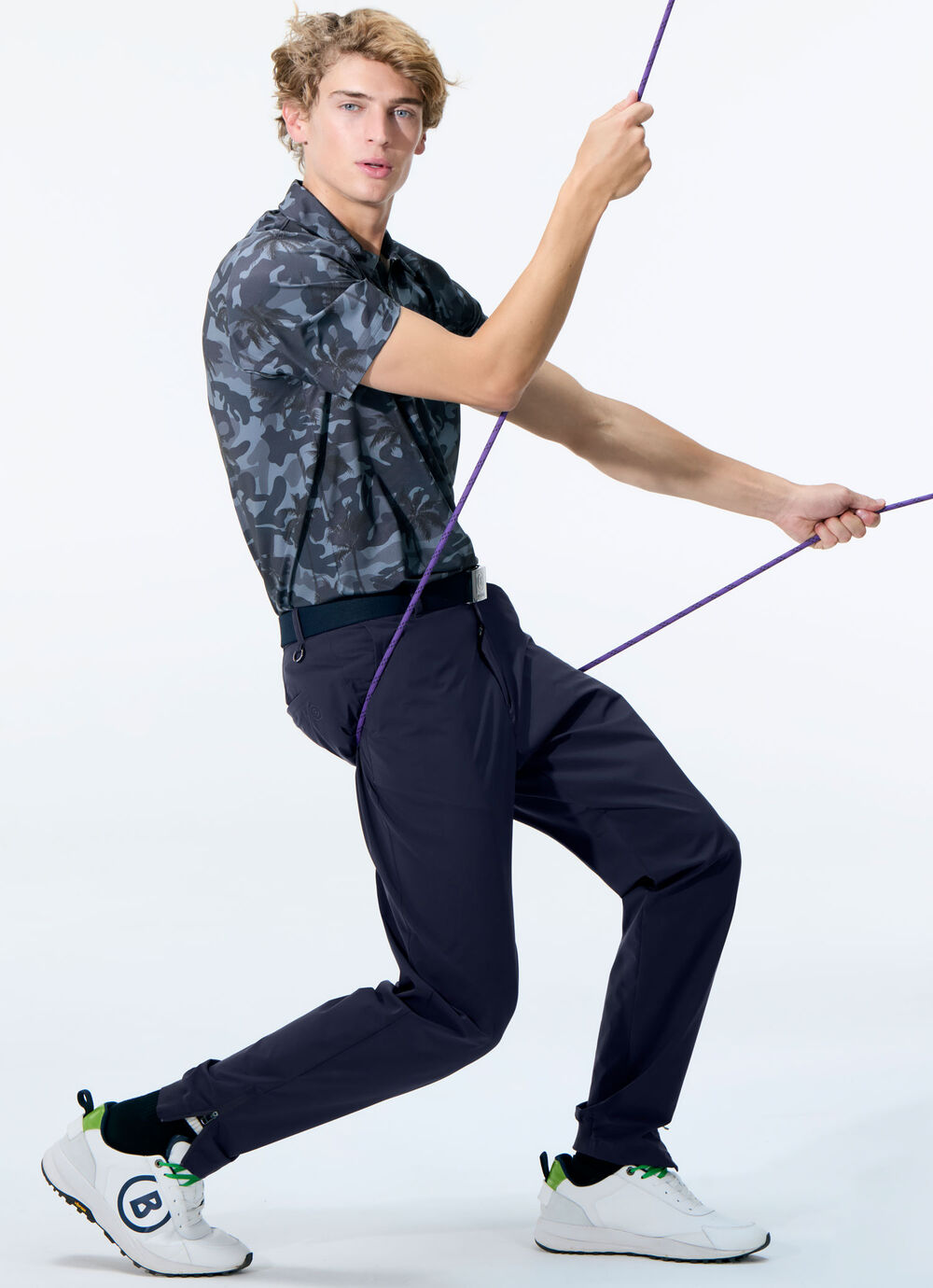 The male model wears dark blue golf pants and a polo shirt with an eye-catching print.