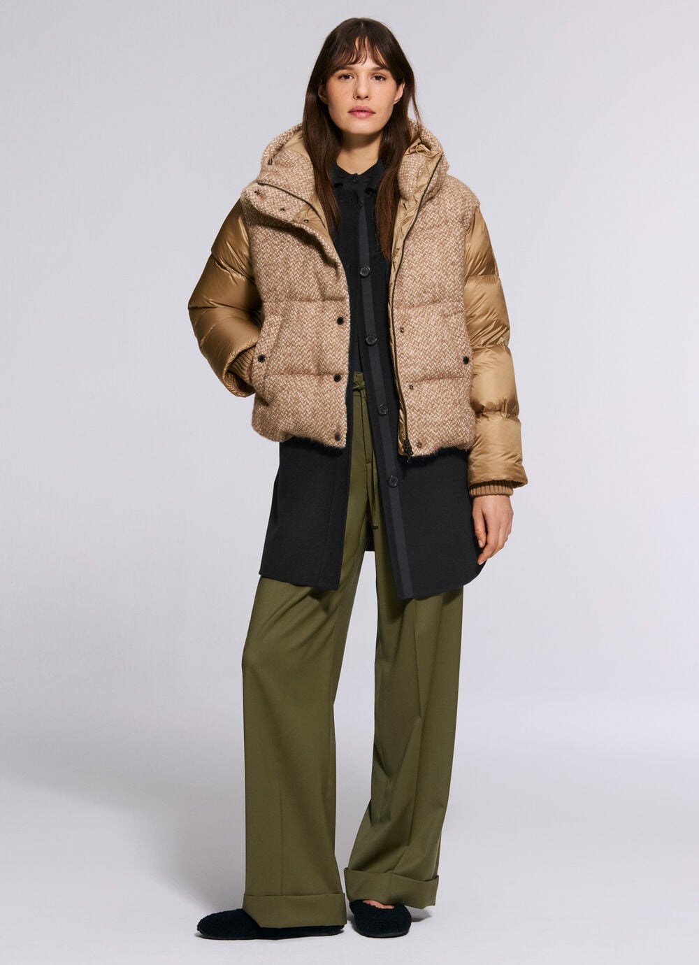 The female model is wearing the Cathy boucl&eacute; down jacket in camel over the Tori jacket and Effy trousers in green.
