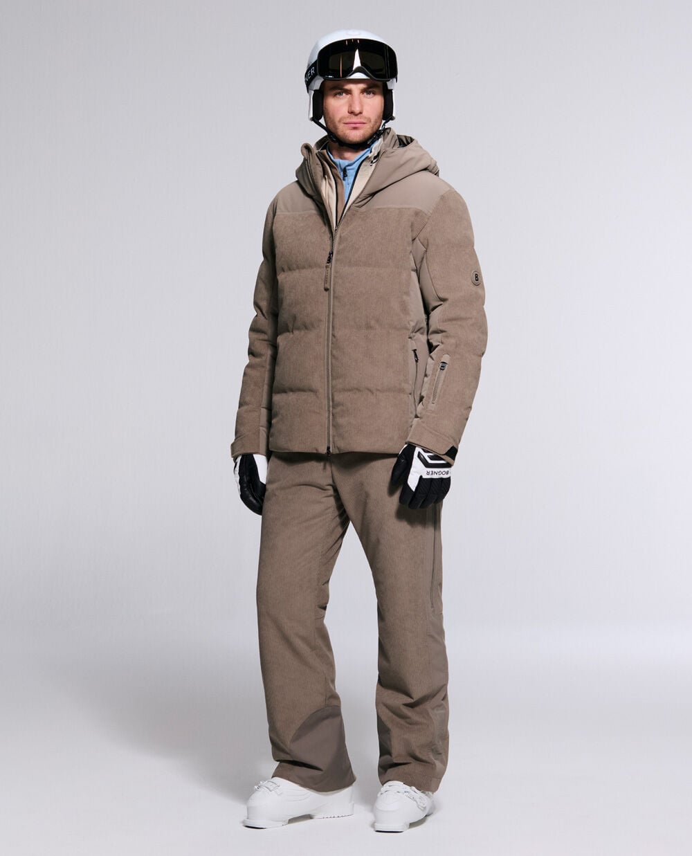 The male model wears the Corsin corduroy ski jacket in hazel with the matching Corven ski trousers and a ski helmet.