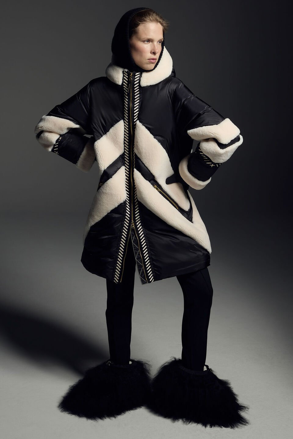 Das Model trägt auf der linken Seite eine detailliert bestickte Jacke, auf der rechten einen schwarzen Parka mit Lammfell.