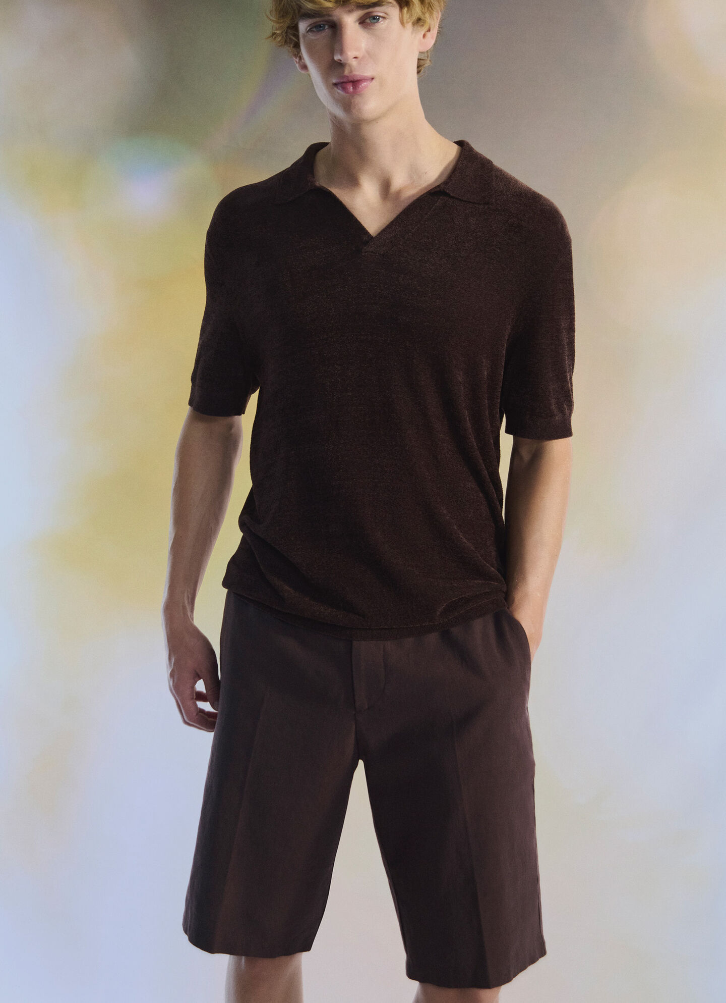 The male model wears a knitted polo shirt and Bermuda shorts in dark brown.