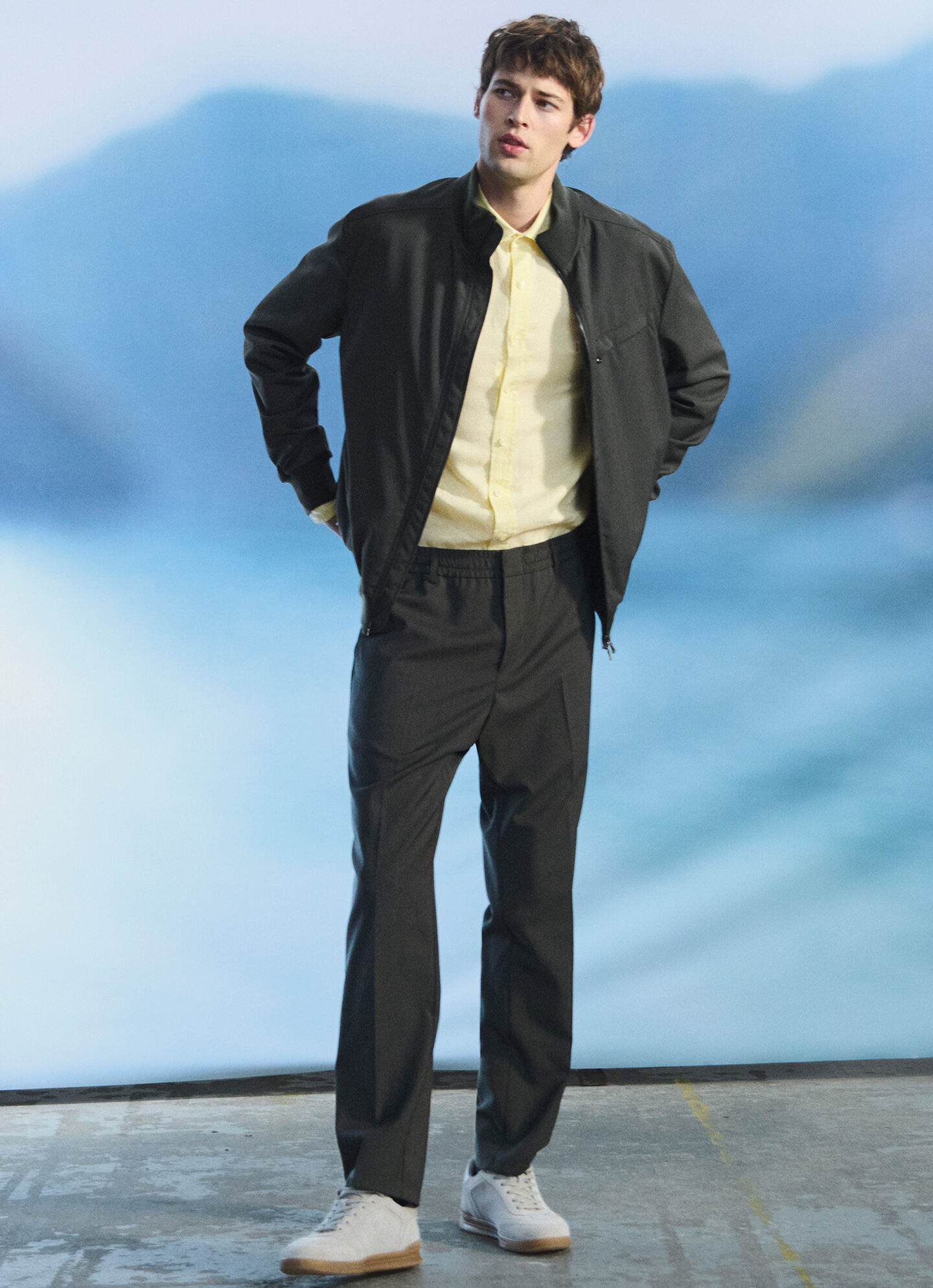 The male model wears a bright yellow polo shirt. A set of blouson jacket and pants in dark green complete the look.