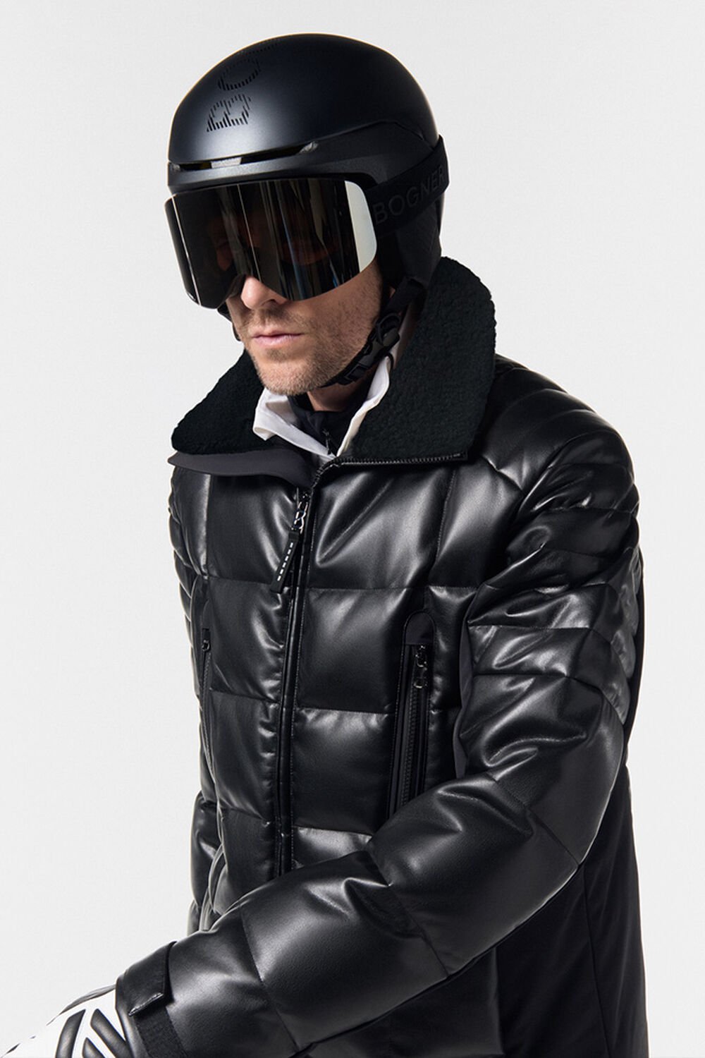 A complete ski outfit with a black quilted ski jacket and matching helmet and ski goggles.