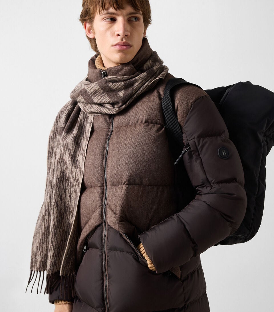 The other male model wears the Jones short down coat in brown, a BOGNER Jacket, paired with a scarf, the Roxter cashmere sweater and Travis straight-leg jeans in dark blue.