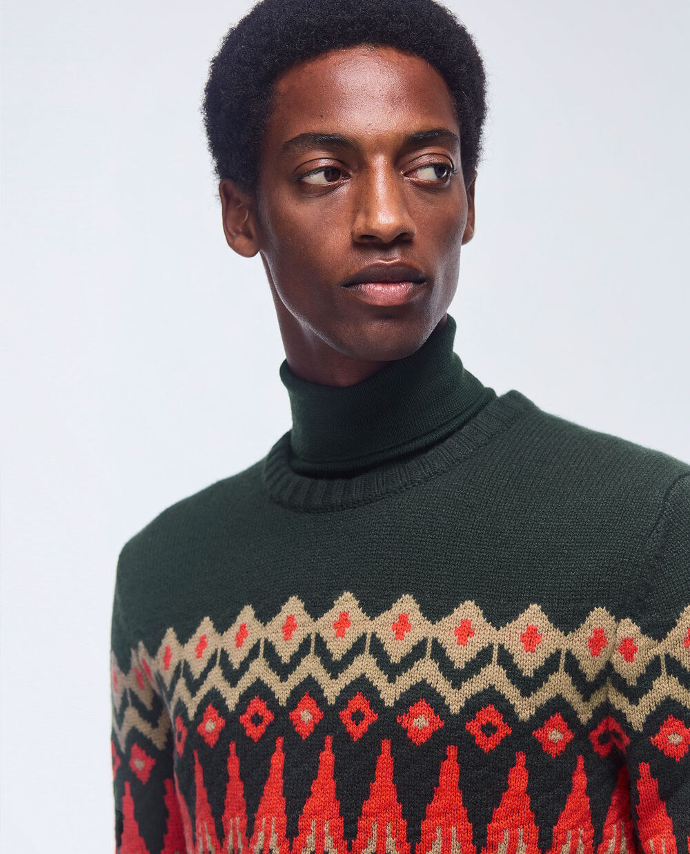 Close-up of a dark green Norwegian sweater with beige and coral-coloured accents