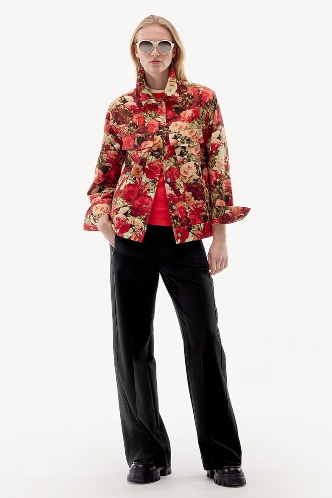 The female model is wearing a denim jacket with a red floral pattern, paired with wide black trousers.