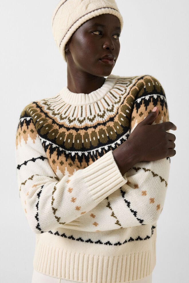  Das Damen Model tr&auml;gt Norweger-Pullover Ingrid mit Muster in Erdt&ouml;nen aus Kaschmir, dazu ein farblich passendes Stirnband.