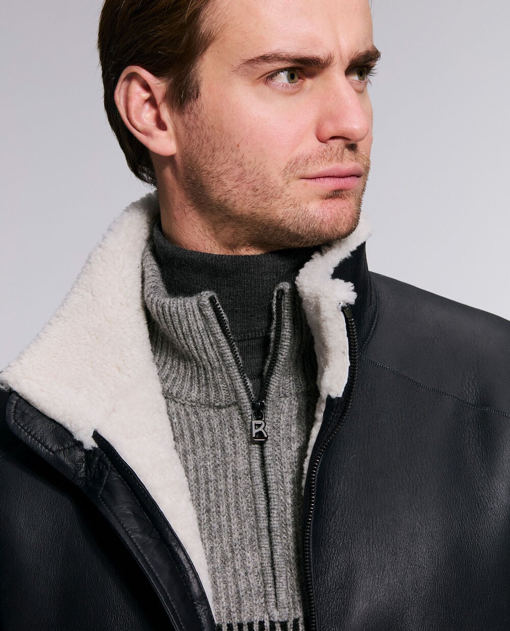The model is wearing the Aleco leather jacket with lambskin fur over the Loris half-zip pullover with logo lettering.