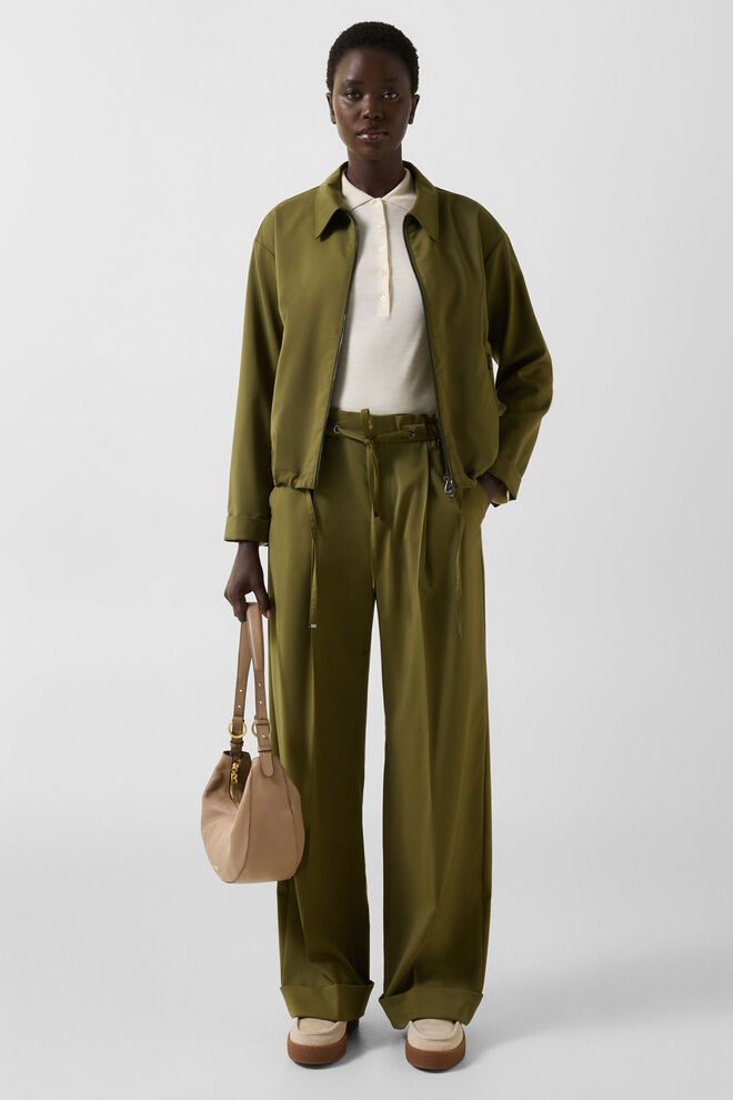 The model is wearing an olive green ensemble comprising the Elody jacket and Elfy trousers with decorative pleats.
