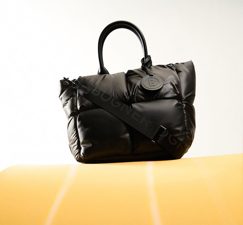 The voluminous quilted black shopper bag has a wide logo strap.
