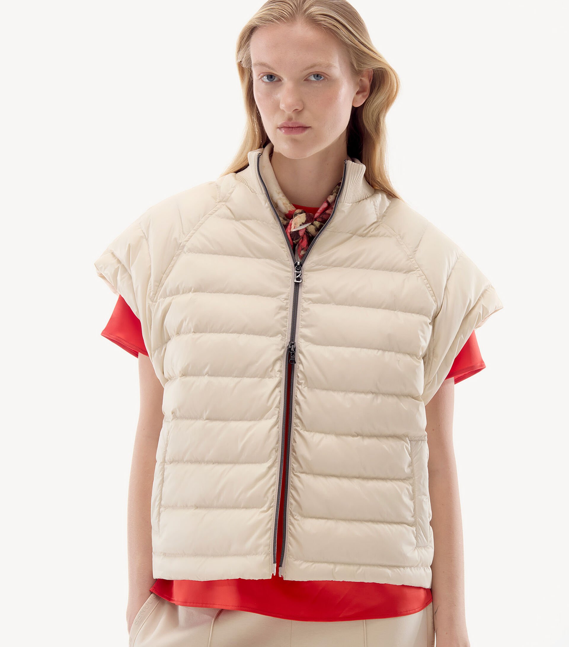 Close-up of female model. She is wearing a beige down gilet with a red shirt.