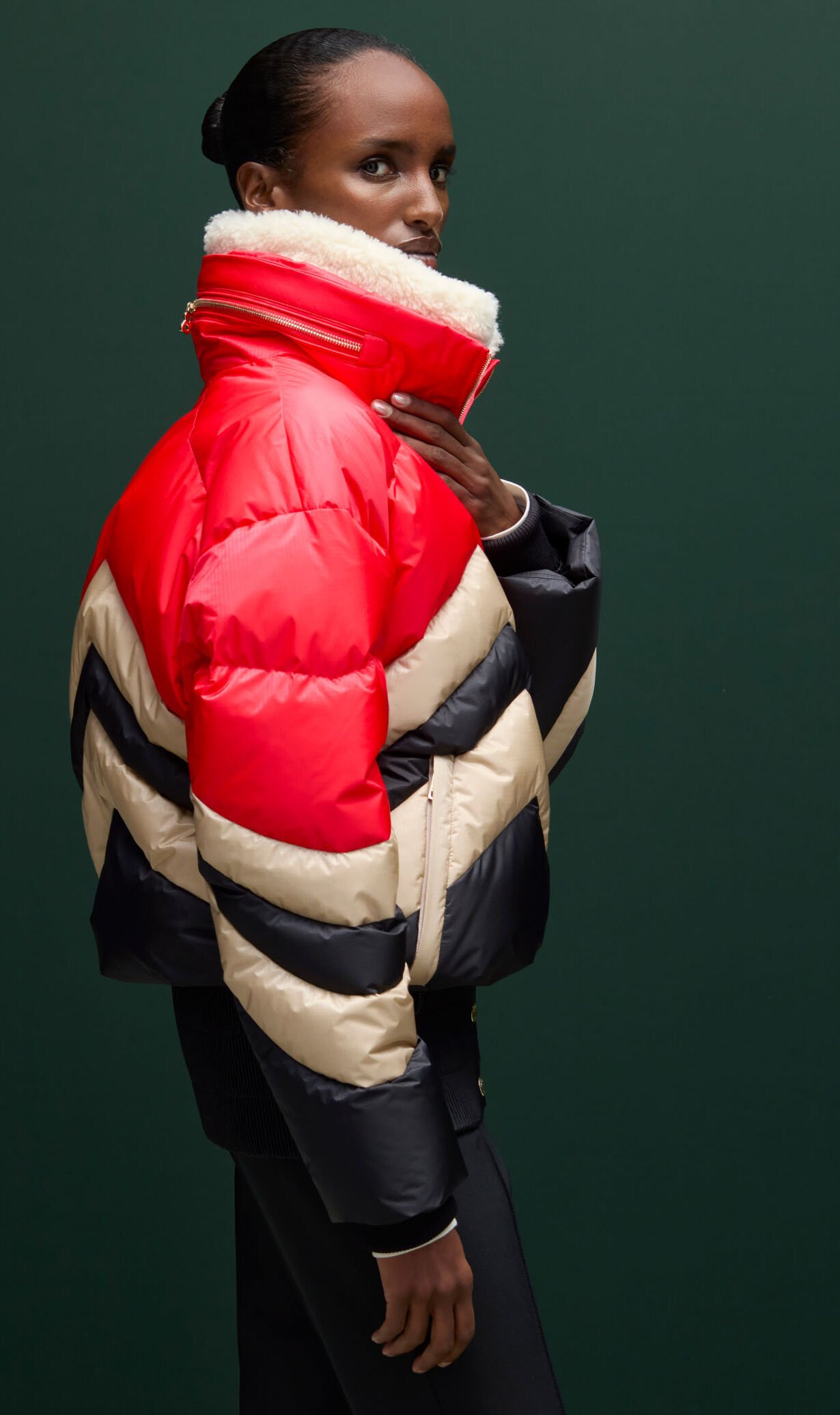 Het vrouwelijke model draagt een zwart met rood en beige donzen ski-jas met een groot doorgestikt W-patroon. Het vrouwelijke model draagt een zwart met rood en beige donzen ski-jas met een groot doorgestikt W-patroon.